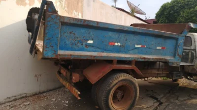 Caminhão de materiais de construção colide contra muro de residência
